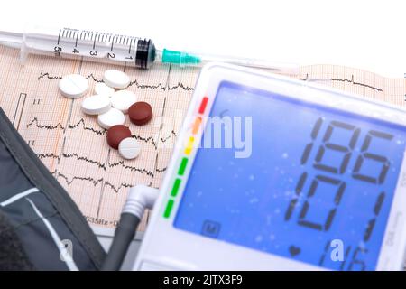 digital sphygmomanometer and heart drugs over electrocardiogram and us dollars near conceptual photo Stock Photo