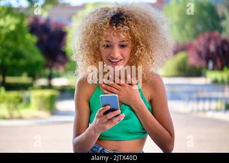 Young Brazilian woman using the smartphone surprised. Stock Photo