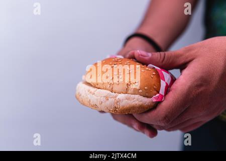 Two hamburger buns on an isolated white background. Hands holding a hamburger. Person about to prepare a hamburger. Stock Photo