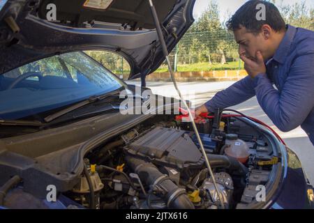 man with broken down car due to low battery. Ignition with cables Stock Photo