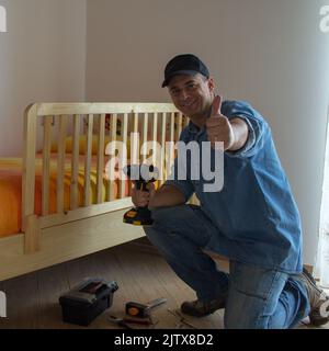 Young handyman dad smiling after mounting his children's bed protector. Housework and bricolage Stock Photo