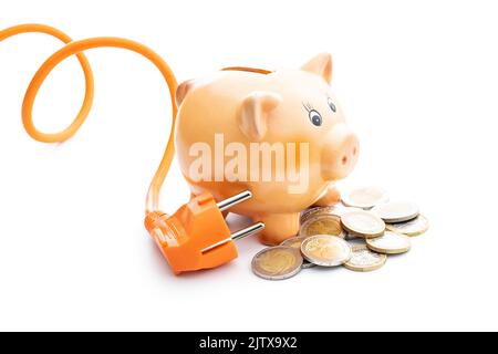 Orange electric plug, coins and piggy bank on the black background ...
