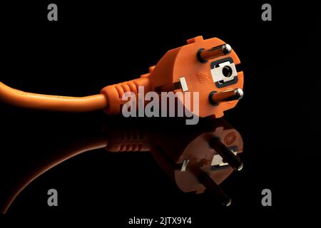 Orange electric plug on the black background. Stock Photo