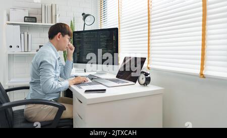 Software development concept, Male programmer looking data on laptop and typing codes on keyboard. Stock Photo