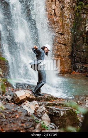 young pretty woman hiking enjoying view of waterfall Stock Photo