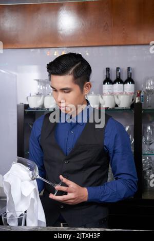 Portrait of young Vietnamese waiter wiping wine glass Stock Photo