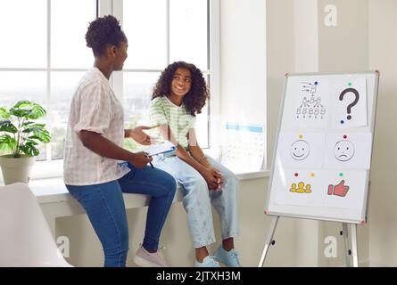 African american girl on consultation with school psychologist sitting on windowsill. Stock Photo