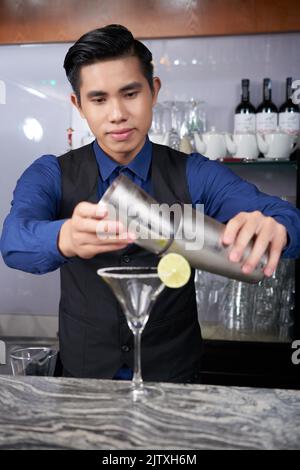 Young Vietnamese professional barman making margarita cocktail Stock Photo