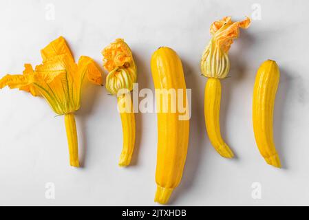 Fresh yellow zucchini or squash with flowers on white background. Top view. Organic vegan food. Fresh harvested vegetables. Stock Photo