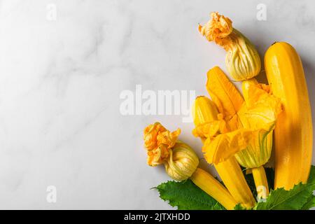 Fresh yellow zucchini or squash with flowers on white background. Top view with copy space. Fresh harvested vegetables Stock Photo