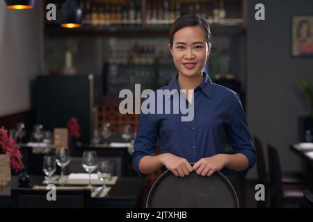Portrait of pretty Vietnamese waitress with empty tray Stock Photo