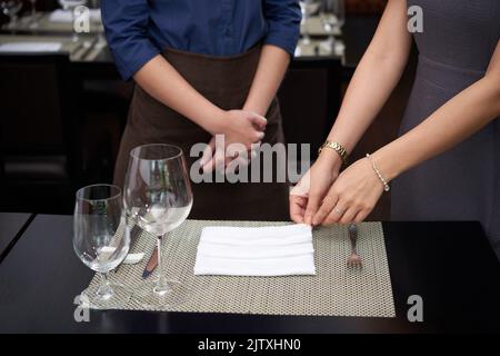 Cafe owner explaining waitress how to fold napkins Stock Photo