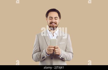 Happy elegant man uses variety of applications on modern mobile phone to order various services. Stock Photo