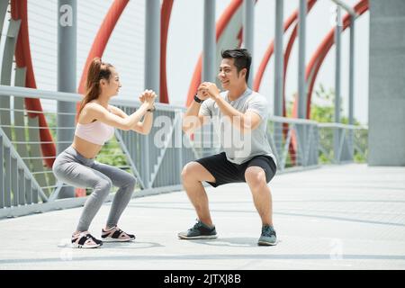 Happy young Vietnamese couple doing squats together Stock Photo