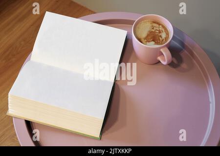 Open book and cup of coffee on the pink table Stock Photo