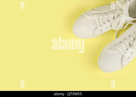 White female sneakers on yellow background with copy space. top view, flat lay. Fashion mockup Stock Photo