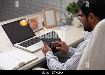 Businessman sitting at table and using application on digital tablet Stock Photo