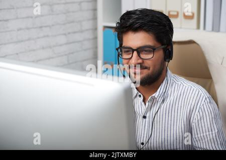 Smling Indian businessman in headset counsulting client Stock Photo