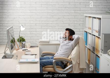 Young Indian business executive daydreaming in his office Stock Photo