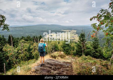 Female traveler use smartphone to take picture of Jizerka village,Bukovec,Czech Republic.Travel concept and technology.Tourist taking picture of natur Stock Photo