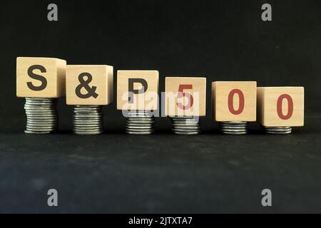 S&P 500 stock market index crash and bear market due to financial crisis and recession in US. Wooden blocks in with coins in dark black background. Stock Photo