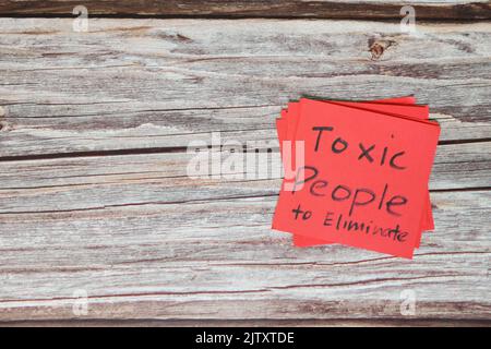 List of toxic people to eliminate concept. Red sticky note in wooden background with copy space. Stock Photo
