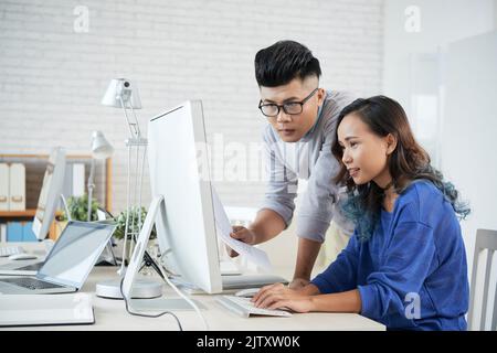 Two colleagues discussing presentation on computer at office Stock Photo