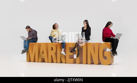 Collage. Young motivated, concentrated people, employees sitting on 3D letters of marketing word and working on laptop Stock Photo