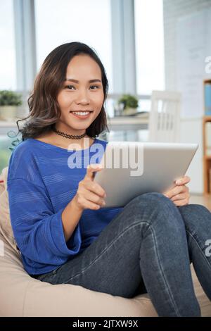 Portrait of young smiling businesswoman sitting and using touchpad Stock Photo