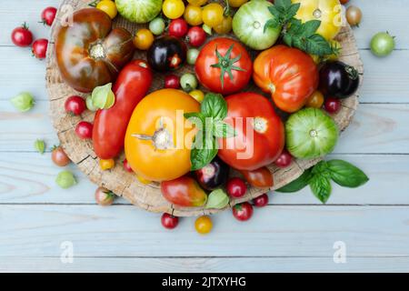 Different varieties kind of red, yellow, green and black tomato mix on wooden table. Fresh assorted colorful summer tomatoes background, close up. Food photography Stock Photo