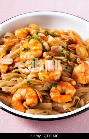 Pad thai with shrimp and peanuts on a pink background. Stock Photo