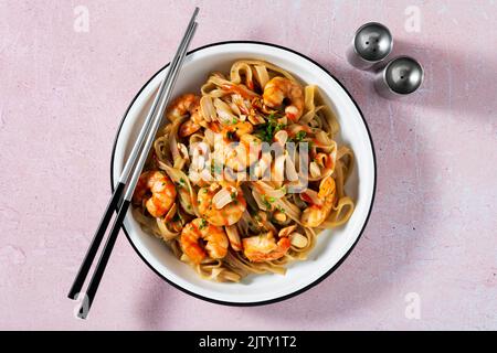 Pad thai with shrimp and peanuts on a pink background. Stock Photo