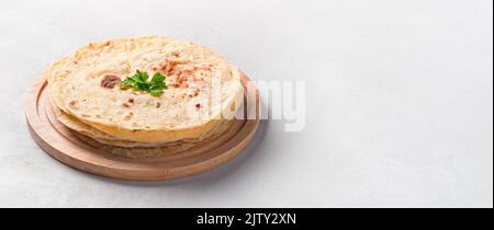 Indian, traditional chapati cakes with fresh herbs on a gray background. Stock Photo