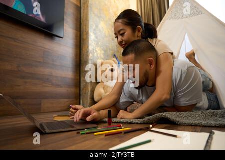 Pretty asian woman lying on back of smiling man Stock Photo