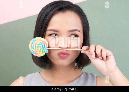 Face of young Asian woman posing with lollipop Stock Photo