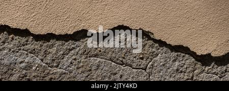 Old sandstone wall with thick pieces of plaster broken off Stock Photo