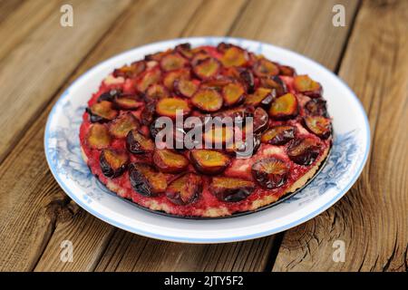 Upside down plum cake on wooden background Stock Photo
