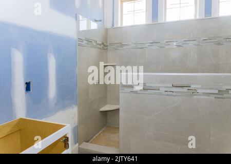Designer renovation construction bathroom with interior of master bathroom with laying ceramic tile to wall Stock Photo