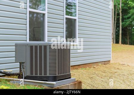 In the vicinity of a new house, an electric air conditioner is being installed outside for residential use Stock Photo