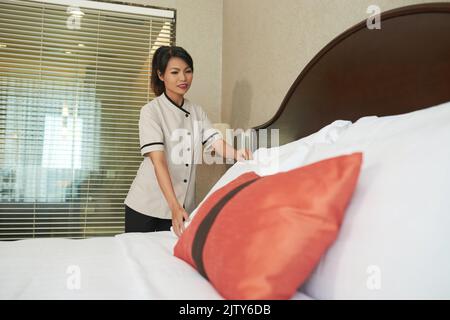 Pretty Vietnamese maid making bed for the guets Stock Photo