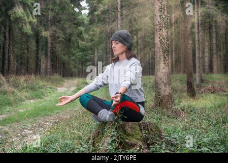 Yoga woman sitting and meditating in a forest. Stock Photo
