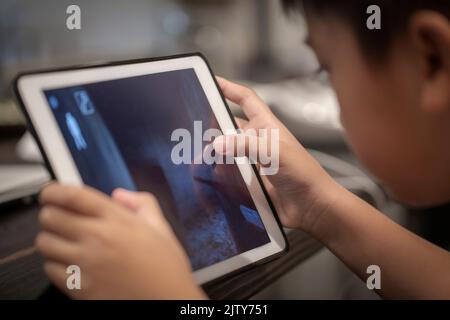 Asian boy playing game on digital tablet at home , Children watching cartoons on digital taplet or smartphone Stock Photo