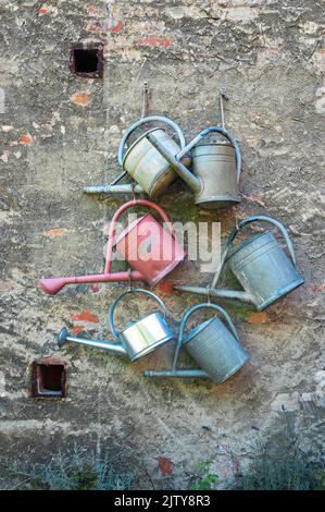 Old watering cans hanging on the wall of a house in Gardelegen, Germany Stock Photo