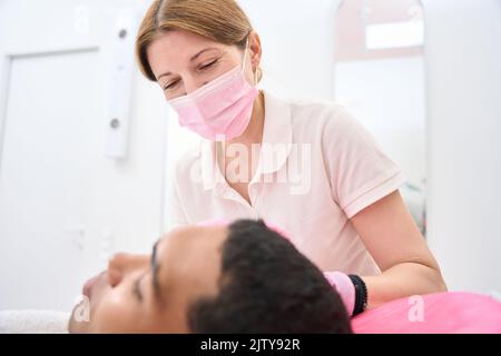 Aesthetic clinic dermatologist treating male patient skin Stock Photo