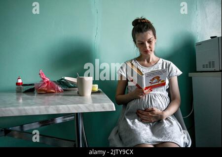 ZAPORIZHZHIA, UKRAINE - SEPTEMBER 1, 2022 - A pregnant woman reads a book in a ward at maternity hospital N9, Zaporizhzhia, southeastern Ukraine. Empl Stock Photo