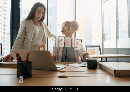 Woman talking to her colleague in office with large window Stock Photo
