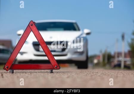 Car breakdown concept. Warning stop triangle close-up on the background of the car Stock Photo