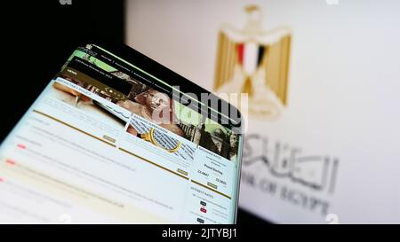 Mobile phone with website of monetary authority Central Bank of Egypt (CBE) on screen in front of logo. Focus on top-left of phone display. Stock Photo