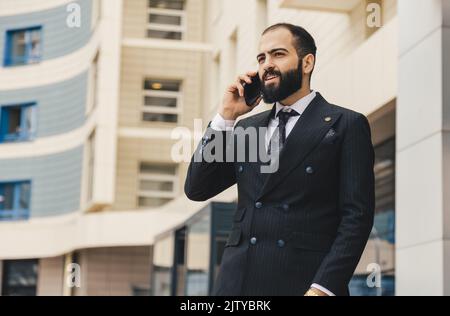 Portrait of a business man outdoors using the phone against the backdrop of a glass building downtown. Stock Photo