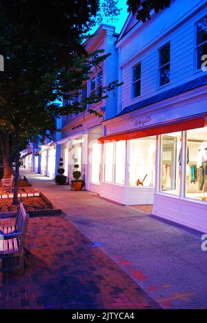 High end stores in East Hampton, Long Island, one of the towns of the Hamptons, are illuminated as twilight Stock Photo